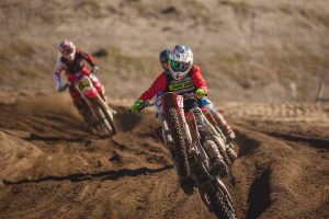 Dirt bike riders racing in fierce competition on a track.