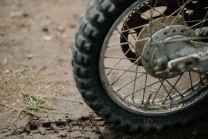A rear dirt bike tire rests on muddy ground.