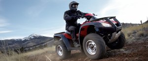 Man riding on a red Honda ATV in the mountains
