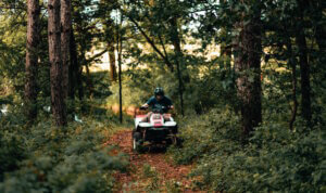 Man riding an ATV through trees